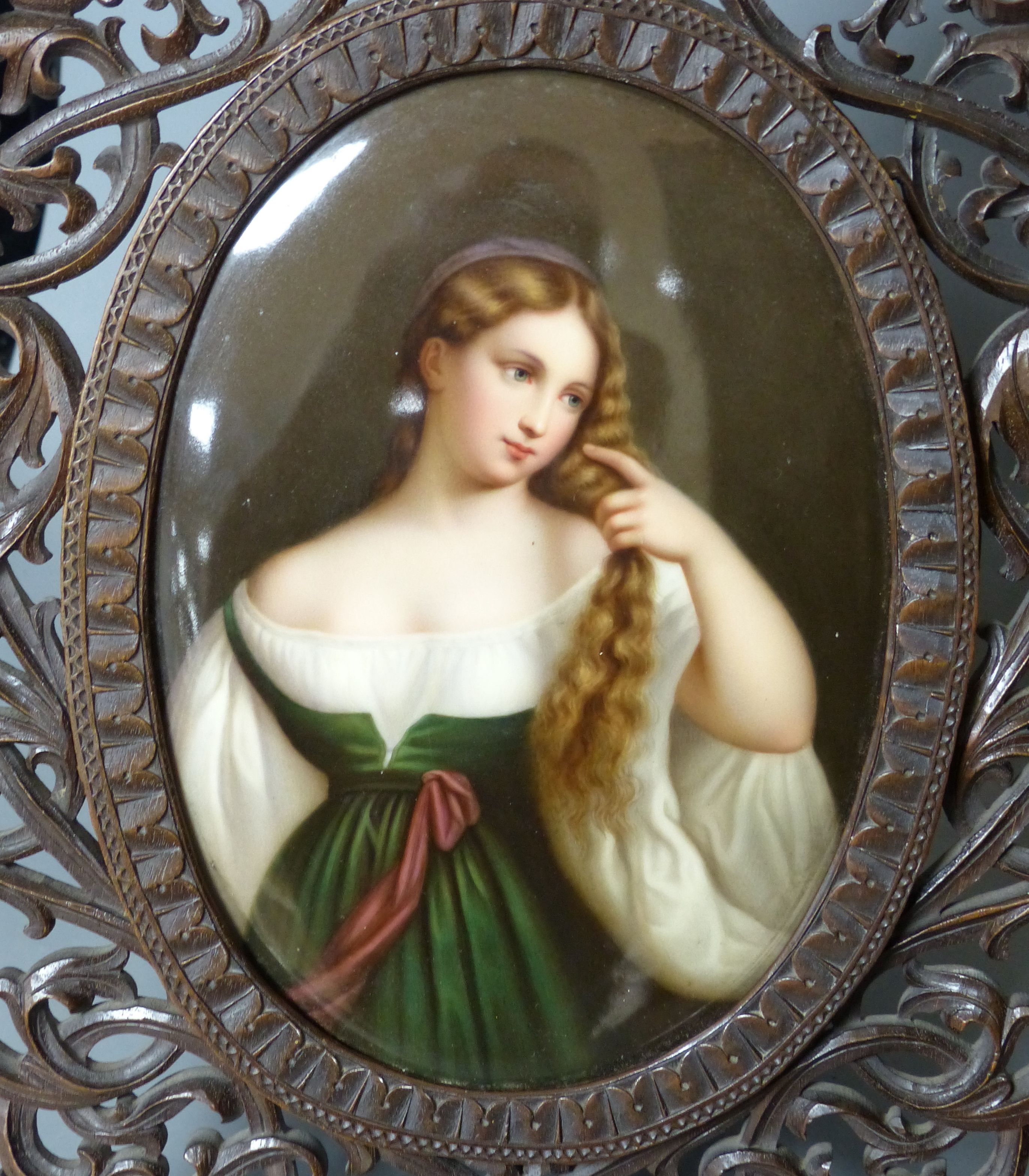 A large 19th century painted Paris porcelain plaque of a girl in a Black Forest carved frame, height 44cm overall